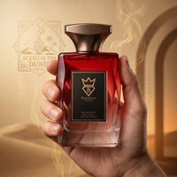 Hand holding a Bujairami Red Static Eau de Parfum 100ml bottle against a golden desert backdrop